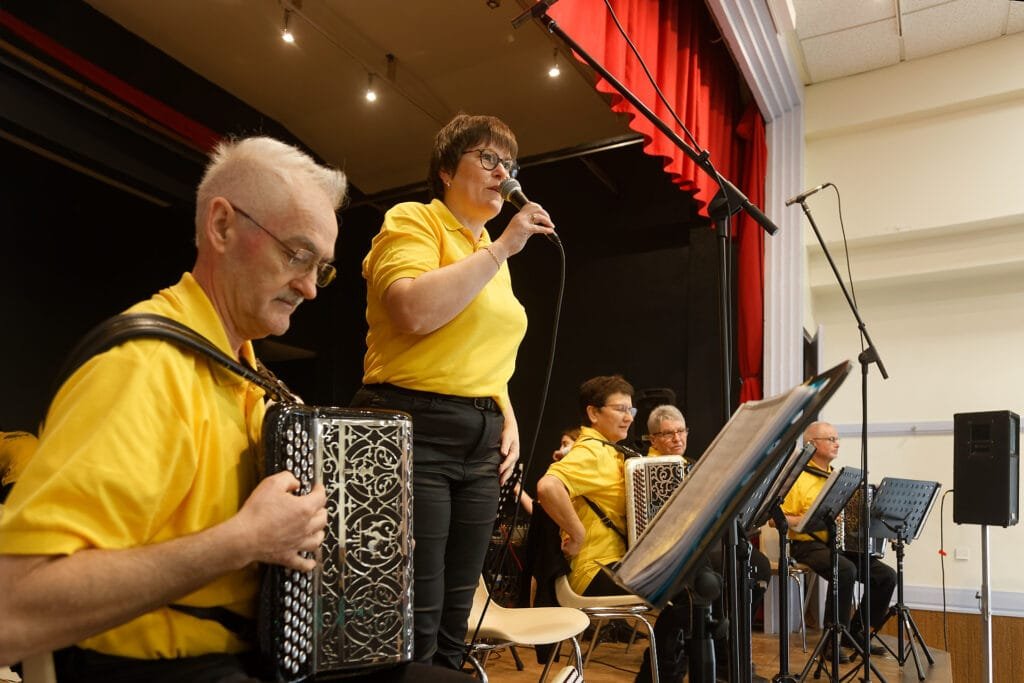 L’orchestre Fa Si l’Accordéon en pleine performance sur la scène de la salle Clemenceau à La Réorthe, avec 11 accordéonistes, deux trompettistes et trois chanteuses.