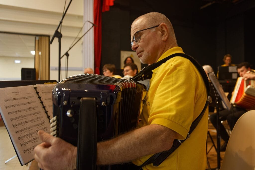L’orchestre Fa Si l’Accordéon en pleine performance sur la scène de la salle Clemenceau à La Réorthe, avec 11 accordéonistes, deux trompettistes et trois chanteuses.