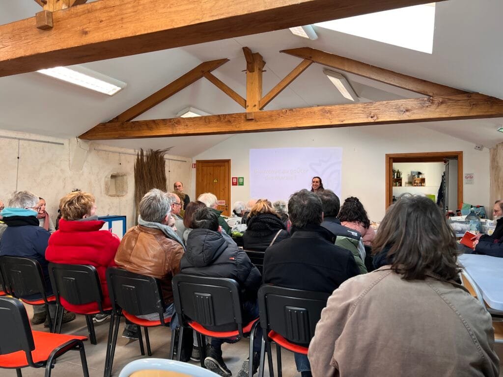 Des participants rassemblés autour d’un goûter champêtre, partageant crêpes et échanges sur la préservation des zones humides.