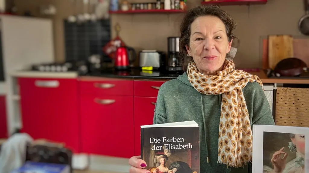 Sabrina Kiefner chez elle, tenant son nouveau roman "Les couleurs d'Élisabeth", un livre hommage à la portraitiste Élisabeth Vigée Le Brun.