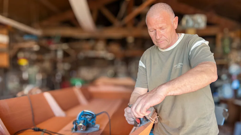Michel apporte les dernières finitions à sa barque en acajou, dans son atelier de Mareuil-sur-Lay. © Vendée Gazette